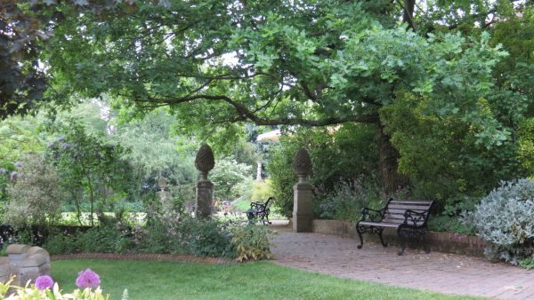 Wide footpath under trees with seat and two features on plinths.